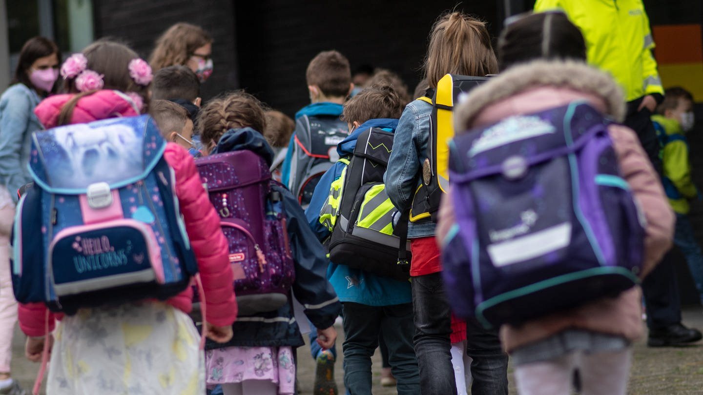 Kinder mit ihren Schultaschen warten an einer Gundschule. In Appenheim gibt es Ärger um die Zusammenlegung von zwei vierten Klassen.