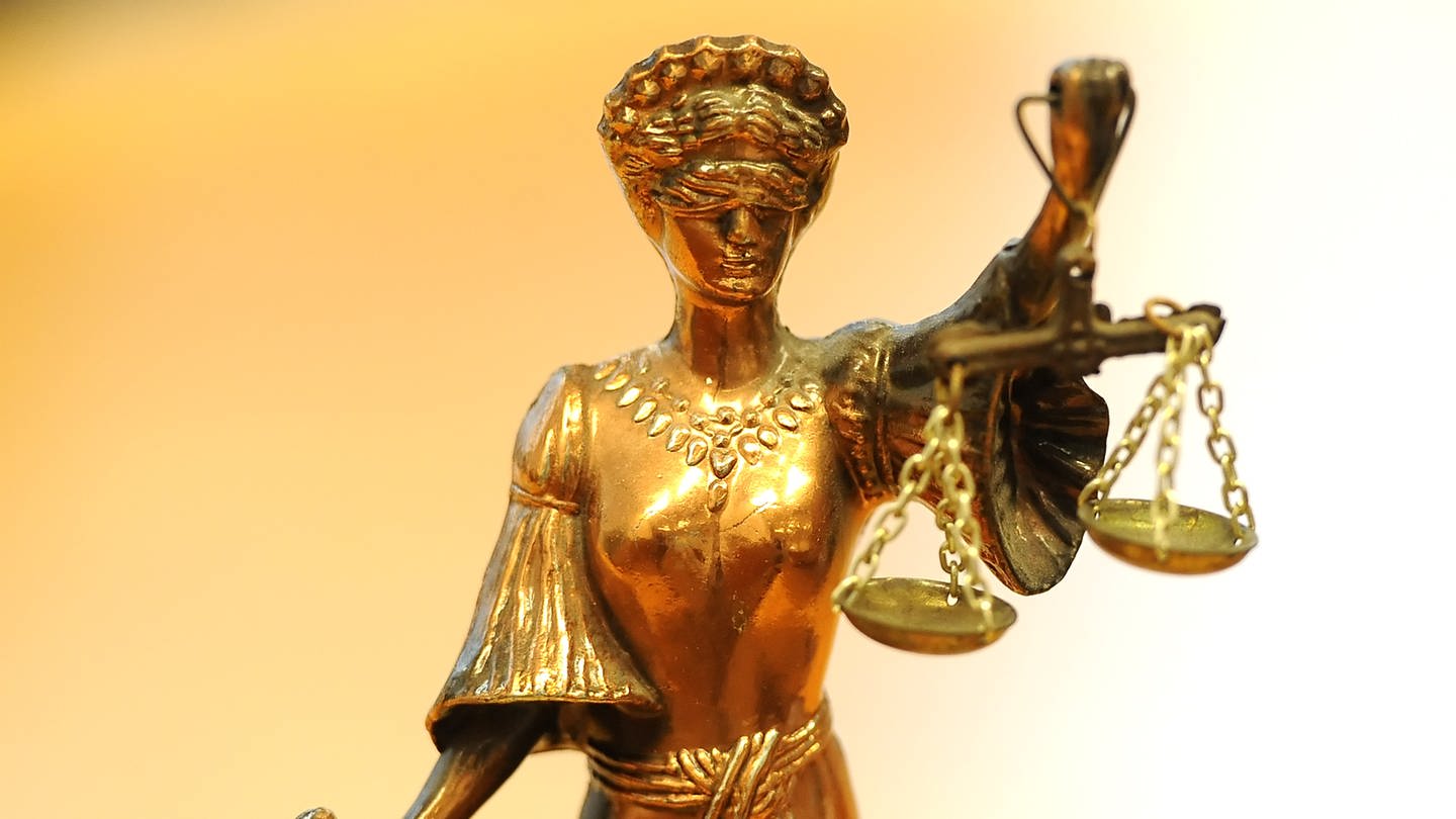 Eine goldfarbene Justitia-Figur steht in einem Gericht.