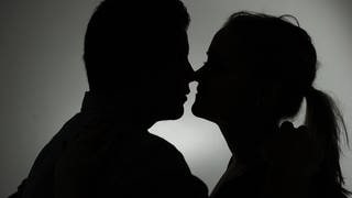 Ein Mann und eine Frau küssen sich. Immer wieder fallen Menschen auf der Suche nach der großen Liebe aber auf Betrüger herein. 