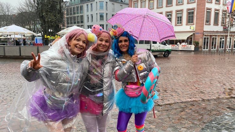 Den drei Närrinnen in Mainz macht der Regen nichts aus - sie feiern trotzdem Weiberfastnacht.