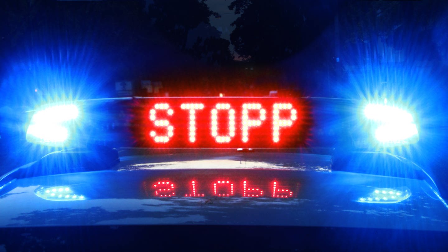 Auf einem Polizeiauto leuchtet in Rot das Wort 