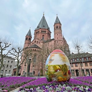 Vor dem Mianzer Dom steht ein großes buntes Osterei. 