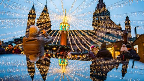 Der Dom und die festliche Beleuchtung auf dem Mainzer Weihnachtsmarkt spiegeln sich in einer glänzenden Oberfläche.