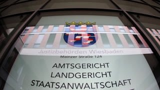 Eine Hinweistafel hängt im Foyer des Justizzentrums in Wiesbaden. Vor dem Landgericht muss sich ein Vater verwantworten, der sein Baby totgeschüttelt haben soll.