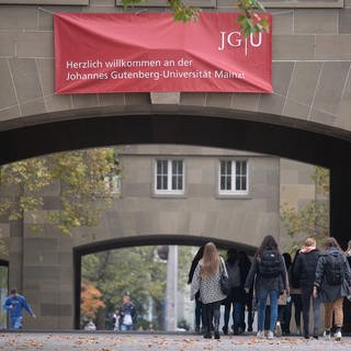 Studierende gehen über den Campus der Johannes Gutenberg-Universität Mainz