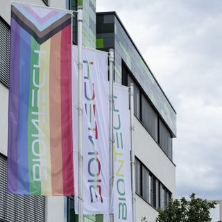Vor der Zentrale von BioNTech an der Mainzer Goldgrube wehen Fahnen, darunter eine Regenbogenfahne