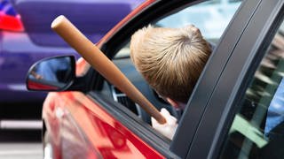 Symbolfoto, Verärgerter Autofahrer droht mit einem Basballschläger