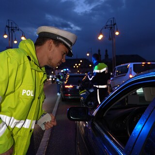 Ein Mainzer Polizist steht am geöffneten Fenster eines Autos und spricht mit dem Fahrer.