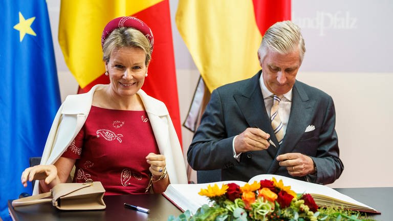 Königin Mathilde und König Philippe tragen sich in das Gästebuch der Landesregierung ein. 
