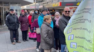 Vor dem Weihnachtsmarkt-Stand der Stadt Worms stehen Menschen Schlange, um alte Glühbirnen kostenlos gegen LED-Lampen umzutauschen.