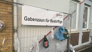 Am Gabenzaun in Bad Kreuznach hängen Tüten mit Spenden