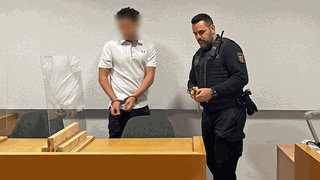 Ein 20-jähriger mutmaßlicher Komplize von Geldautomatensprengern muss sich vor dem Landgericht in Mainz verantworten. Er trägt ein weißes kurzärmeliges Poloshirt und eine schwarze Hose. 
