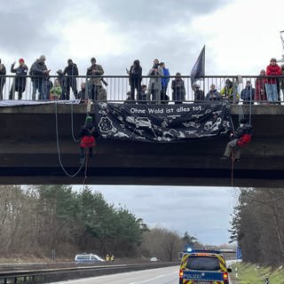 Demonstranten seilen sich von einer Brücke auf die A643 ab
