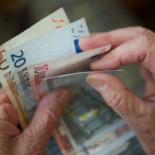 Eine ältere Frau zählt die Geldscheine in ihrem Portemonnaie