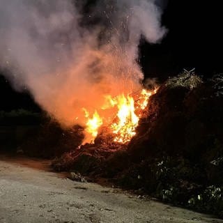 Ein großer Haufen Grünschnitt brennt in der Nacht auf der Kompostanlage.
