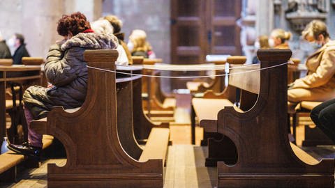 Mehrere Gottesdienstbesucher sitzen in dicken Jacken in den Kirchenbänken im Mainzer Dom
