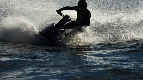 Ein Jetski-Fahrer fährt eine Kurve auf dem Wasser.