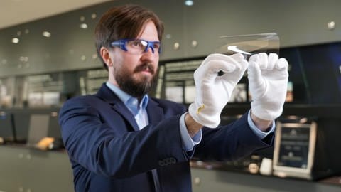 Ein Mitarbeiter von Schott führt vor, wie stark sich das ultradünne Glas von Schott biegen lässt.