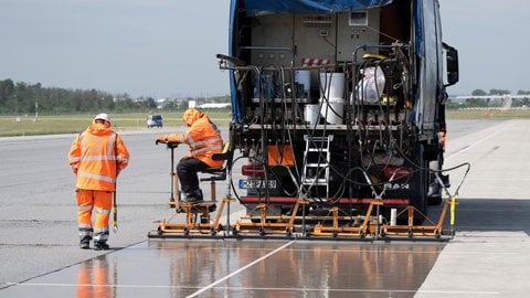 Eine spezielle Flüssig-Grundierung bringen Arbeiter mit einem Spezialfahrzeug auf der Landebahn Nordwest auf dem Flughafen in Frankfurt an.