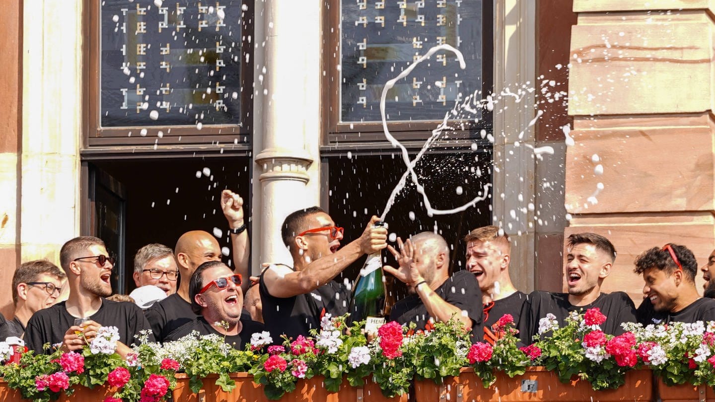 Spieler und Vereinsobere des SVWW feiern auf dem Balkon des Wiesbadener Rathauses den Wiederaufstieg.