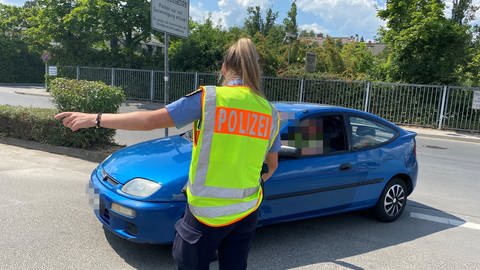 Bei einer Polizeikontrolle in Mainz zeigt eine junge Polizisten einem Autofahrer an, weiterzufahren.