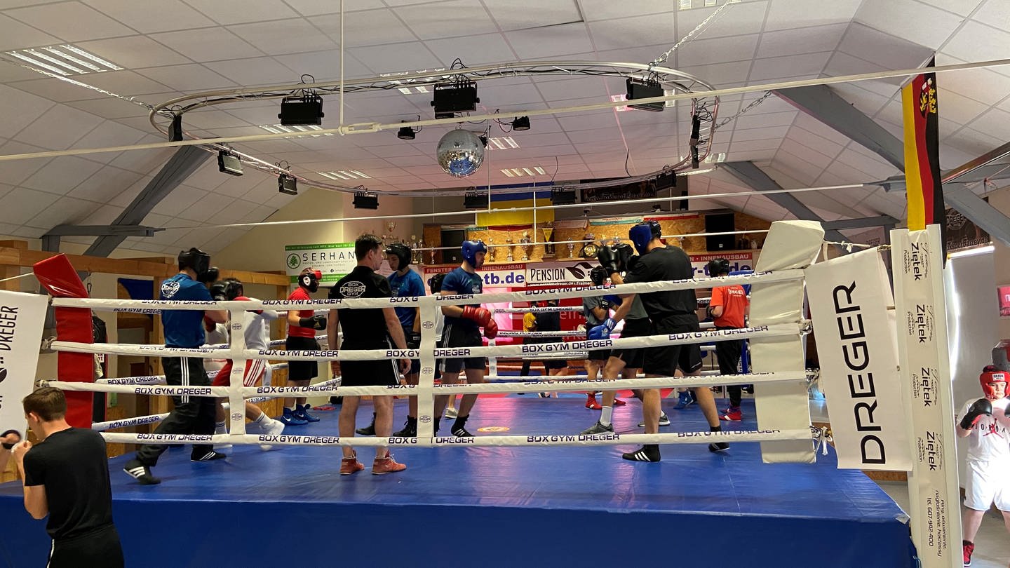 In einem Boxring stehen verschiedene Jugendliche und trainieren.