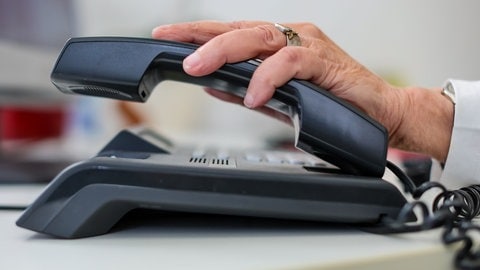 Eine Seniorin hält einen Telefonhörer