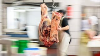 Eine Rinderkeule wird in einer Fleischerei in das Kühlhaus geschoben.