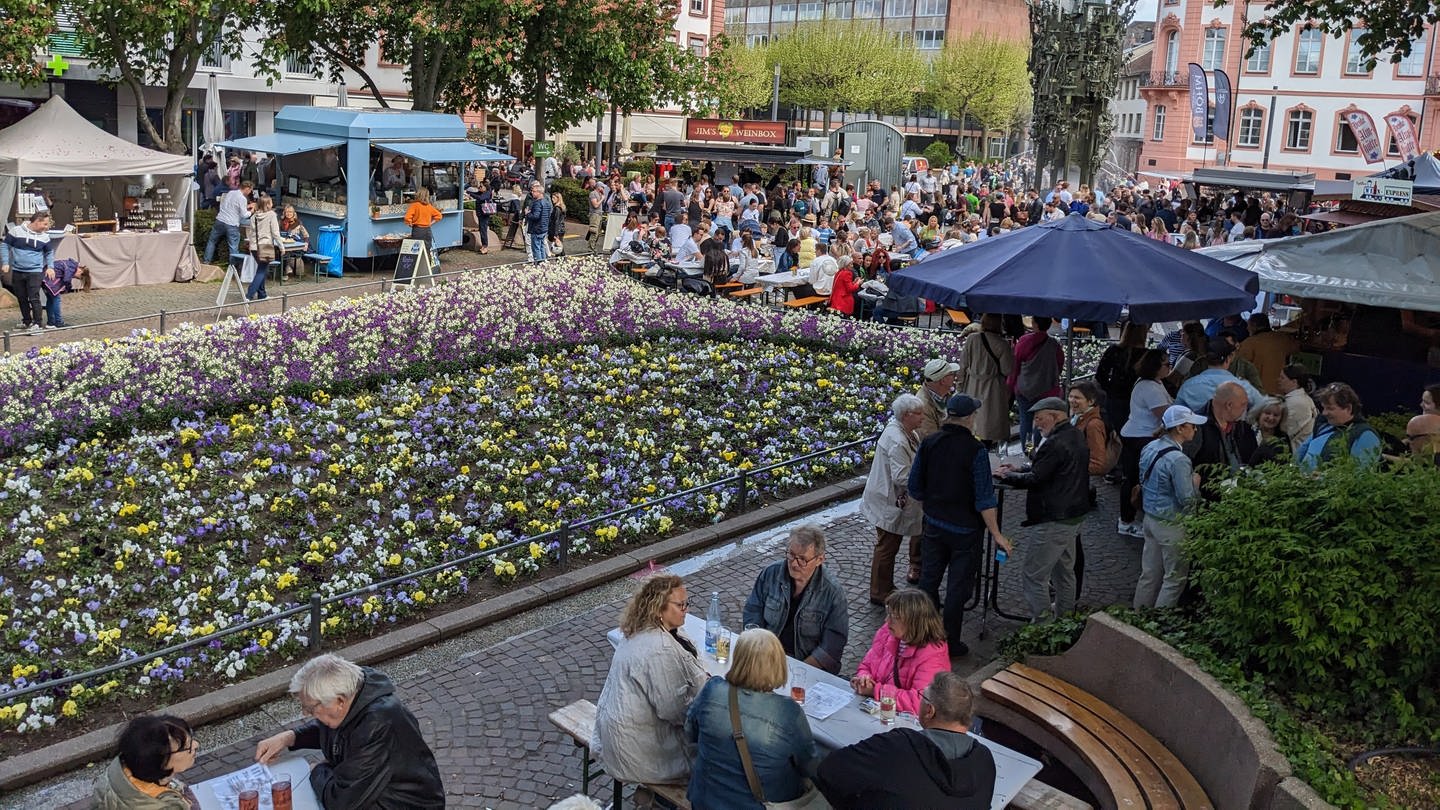 Besucher sitzen und stehen auf dem Mainzer Schillerplatz beim WeinHerbst an Ausschank- und Essensständen.