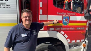 Der Zugführer der Feuerwehr Bingen vor dem Feuerwehrfahrzeug inklusive Drehleiter, das jetzt nach Prizren im Kosovo übergeben wurde.