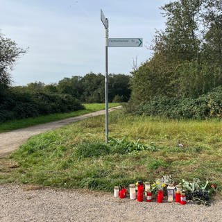 Auf dem Foto stehen mehrere Kerzen am Rand eines Feldweges: Bei der Messerstecherei in Bingen gab es einen Toten, für die Hinterbliebenen soll jetzt gespendet werden