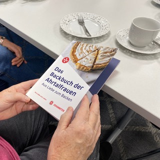 Bachbuch der Ahrtal Frauen, Omas halten Backbuch in der Hand, Backen mit Oma, Omas Backrezepte, Kuchen