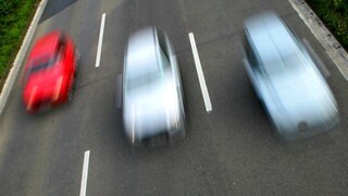 Drei Autos fahren nebeneinander auf der Autobahn.