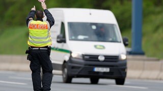 Ein Polizist stoppt einen Sprinter für eine Polizeikontrolle auf der Autobahn. (Symbolbild)