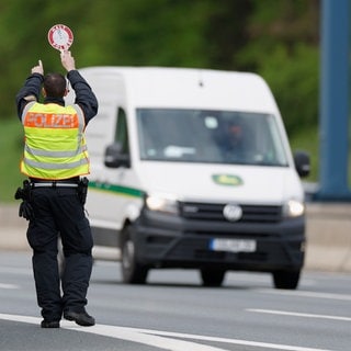 Ein Polizist stoppt einen Sprinter für eine Polizeikontrolle auf der Autobahn. (Symbolbild)