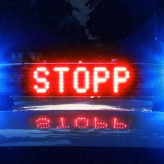 Auf einem Polizeiauto leuchtet in Rot das Wort "Stopp". 