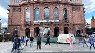 Mainzerinnen und Mainzer schauen sich die Friedenstaube vor dem Mainzer Staatstheater an.