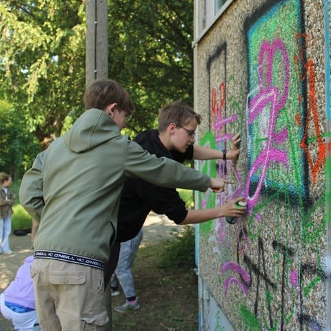 Zwei Jugendliche besprühen das alte Hallenbad in Oppenheim mit Graffiti.