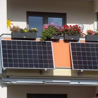 An einem Balkon wurden zwei Solapanele befestigt. Mit der Mini-Photovoltaikanlage kann Strom gewonnen werden. Das spart Energiekosten. 
