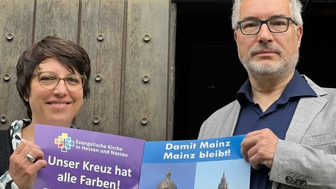 Pfarrerin Eva Lemaire und Dekan Andreas Klodt mit Plakaten vor der Christuskirche Mainz.