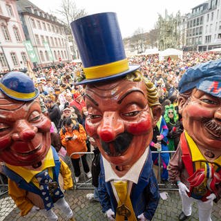 Mainzer Schwellköpp stehen zum Auftakt zur Mainzer Fastnacht auf dem Schillerplatz vor den Feierenden.