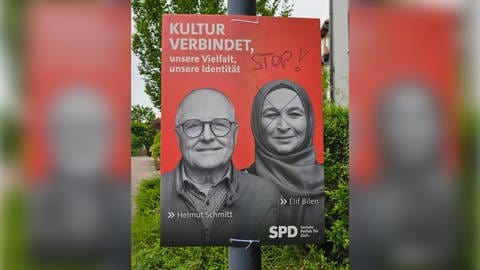 Auf einem Wahlplakat der SPD in Nieder-Olm ist das Gesicht der Kandidatin Elif Bilen mit einem schwarzen Stift durchkreuzt worden. Außerdem steht "Stop!" auf dem Plakat. Elif Bilen trägt ein Kopftuch.