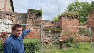 Sascha Schneider zeigt auf bröckelnde Mauern der Schloss Ruine in Bretzenheim.