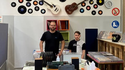 Mitarbeiter und Betreuer stehen in der Vinyl-Ecke zum Schallplatten-Reinigen