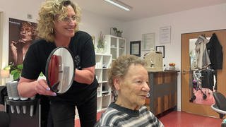 Friseurin Martina Schäfer zeigt ihrer demenzkranken Kundin die neue Dauerwelle.