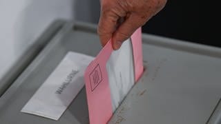 Die ausgefüllten Wahlunterlagen werden in eine Wahlurne geworfen. In Gensingen ist die Wahl zum Ortsbürgermeister jetzt aber verschoben worden.