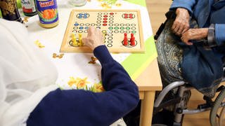 Zwei Seniorinnen aus Afghanistan spielen im Wohnbereich Orient eines Pflegeheims in Hamburg das Gesellschaftsspiel "Mensch ärgere Dich nicht". 