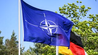 Eine Flagge der NATO weht neben einer Deutschland-Flagge.