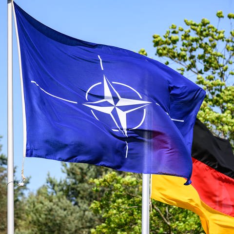 Eine Flagge der NATO weht neben einer Deutschland-Flagge.