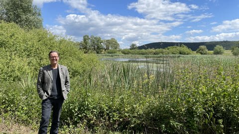 Dieter Gründonner steht vor einem geschützten Teich in der Hügellandschaft bei Odernheim